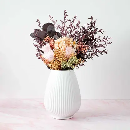 White ribbed ceramic vase placed on a white background highlighting its smooth glossy texture and elegant curved design.