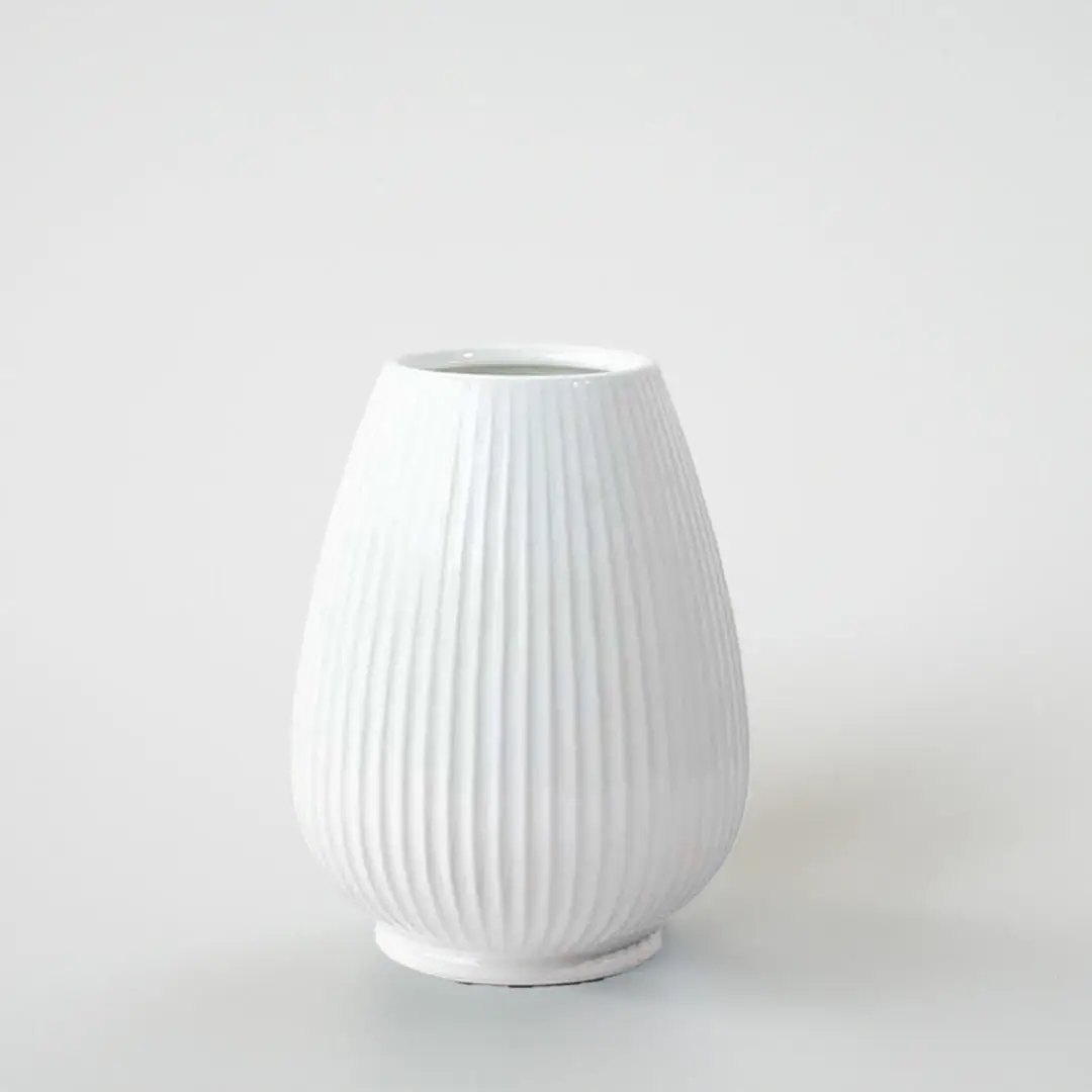 White ribbed ceramic decorative vase with curved silhouette for shelf styling and contemporary home decor displays.