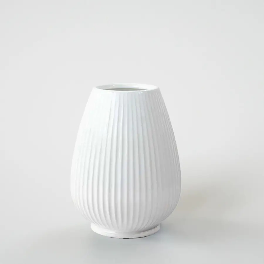 White ribbed ceramic decorative vase with curved silhouette for shelf styling and contemporary home decor displays.