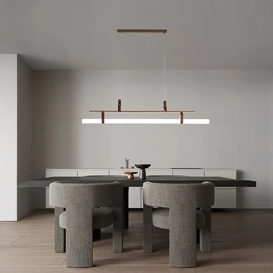 Gold linear pendant light with white tube diffuser styled in a modern dining space adding bright elegant ambient lighting.