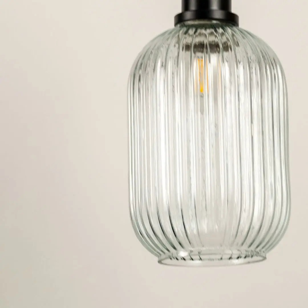 Closeup of clear ribbed glass pendant light with brass details showcasing premium craftsmanship.