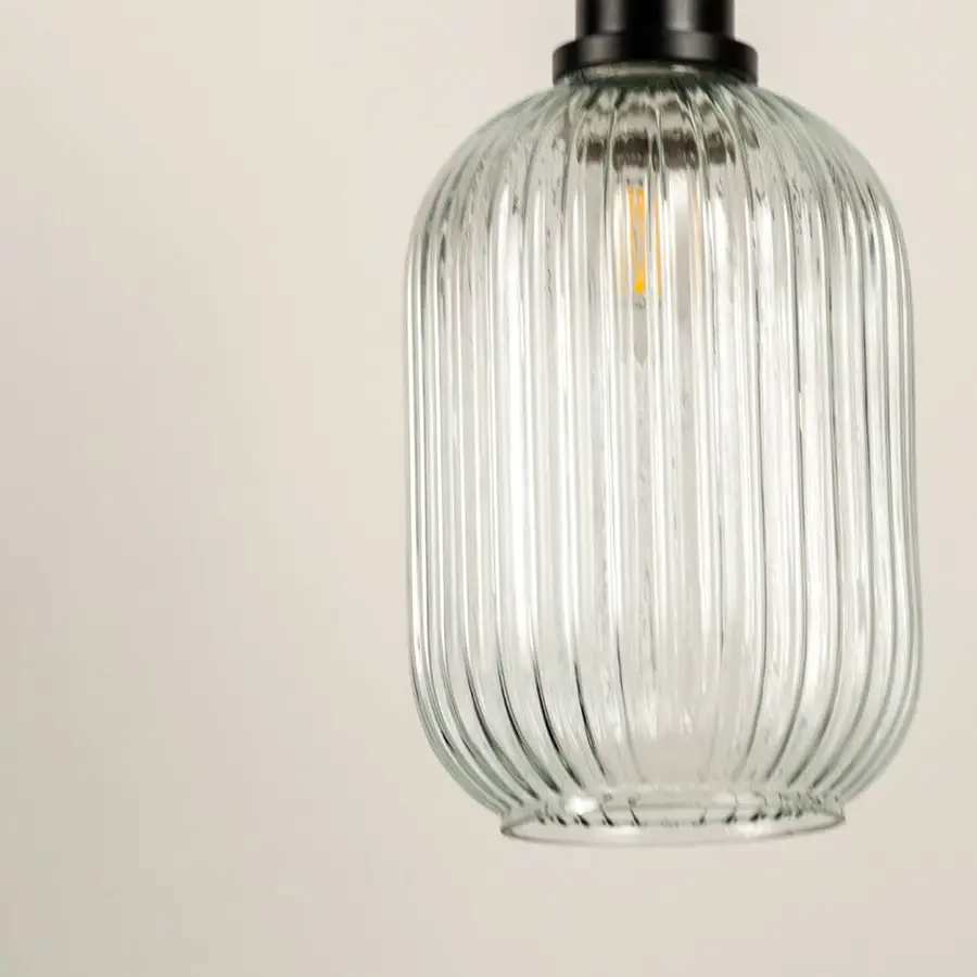 Closeup of clear ribbed glass pendant light with brass details showcasing premium craftsmanship.