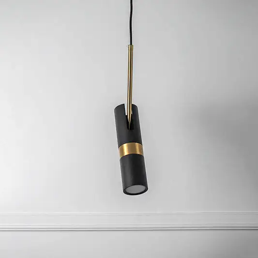 Black cylindrical pendant light with gold accent and hanging cord placed against white background showcasing modern minimal lighting decor styling.