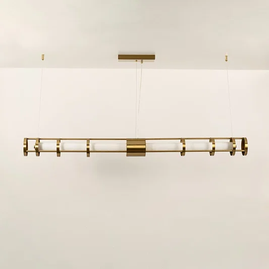 A gold linear ceiling fixture with symmetrical cylindrical elements ideal for modern LED chandelier lighting and luxury designer interior décor applications.