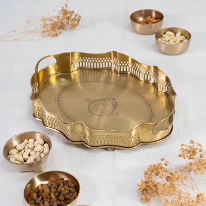 Gold brass serving tray with wavy rim cutwork border and engraved base displayed on plain white background.