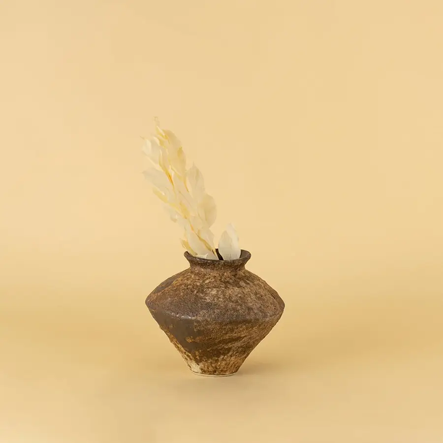 Rustic brown ceramic vase with textured finish styled on wooden table adding earthy elegance to home interior decor