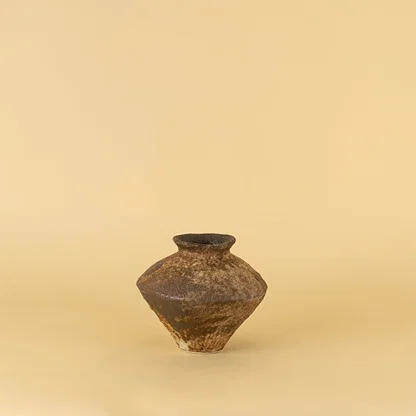 Traditional ceramic pot with earthy brown tone and aged texture placed on beige surface against warm background highlighting antique inspired home decor appeal.