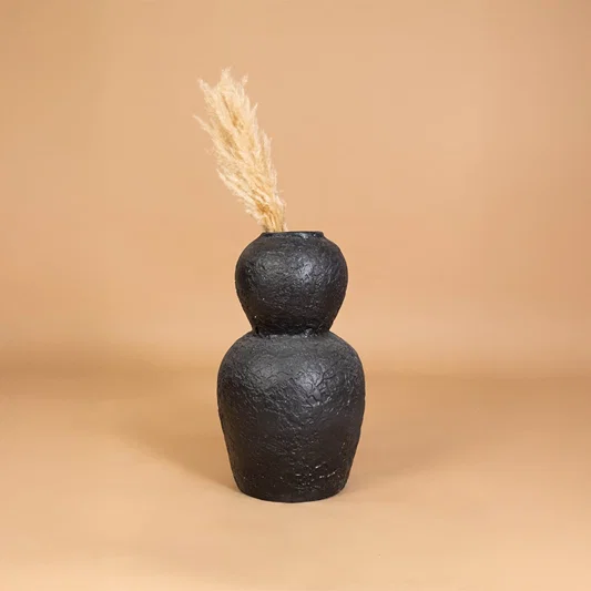 Black textured decorative vase placed in a warm styled interior adding bold artistic character to shelves consoles and living room decor.