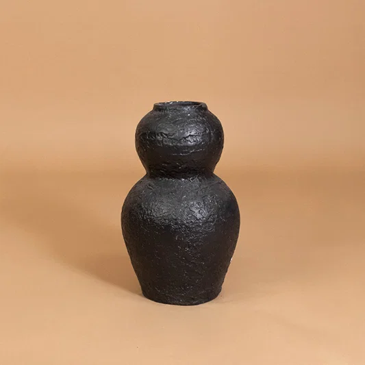Modern ceramic vase in black finish with textured design for table decor or shelf styling contemporary home placement neutral background.