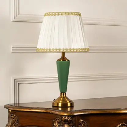Table lamp with green metal base and pleated white shade displayed on a soft white background for clean product viewing.