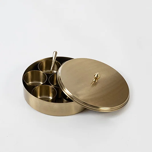 Decorative metal storage box in gold finish with compartments and lid for dining table or decor accessory placement white background.