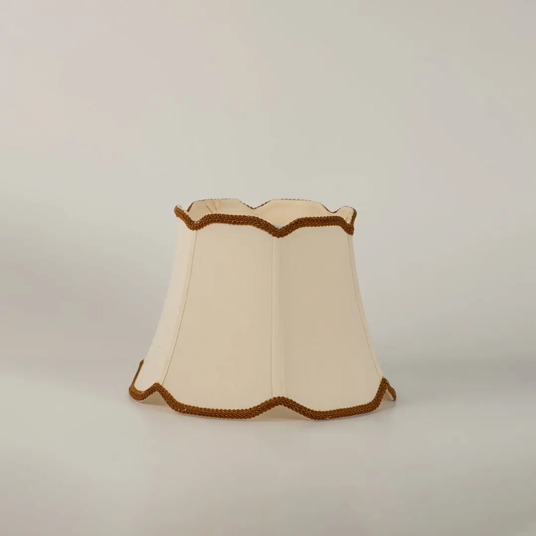 Cream fabric lamp shade with decorative trim shown alone on white background replacement shade for table lamp.