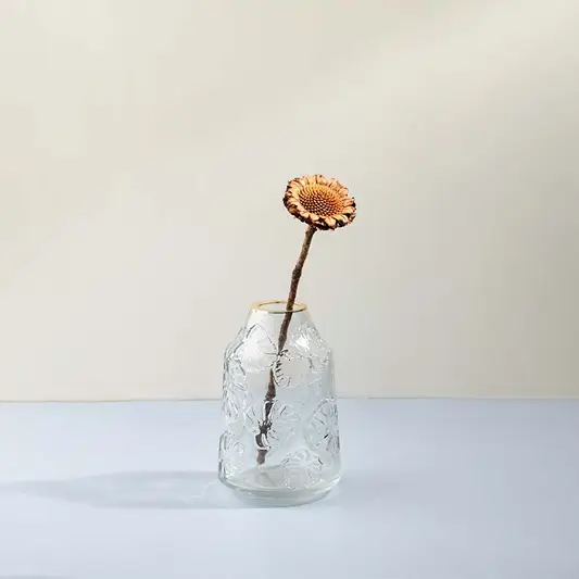 Elegant transparent glass flower vase with embossed design styled with dried flower on wooden table lifestyle image.