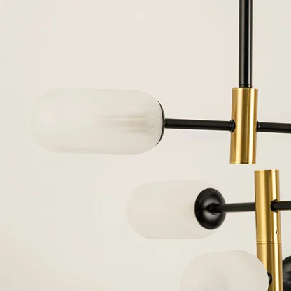 Close view of gold and black chandelier showing frosted glass detailing metallic finish and refined minimalist craftsmanship.