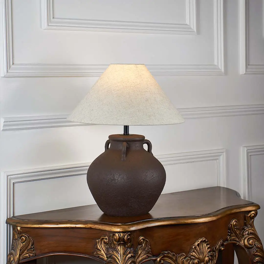 Brown ceramic table lamp with beige linen shade glowing on white background ideal for bedroom lighting table lamp.