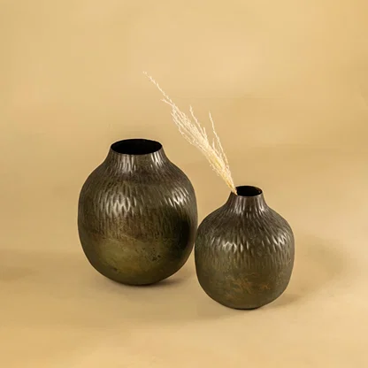 Brown hammered metal vase decor paired with matching pieces bringing earthy modern accents to shelves and living room styling.
