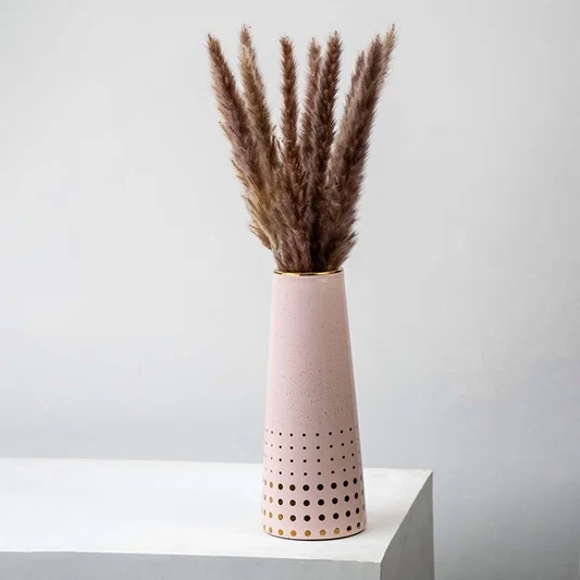 Small dried grass stems arranged in a tall pink vase perfect for earthy boho home décor and modern minimal natural interior styling.