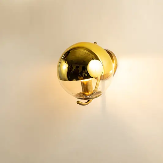 A gold metal and glass wall light shining warmly on a smooth white background creating gentle ambient illumination and adding luxurious modern décor.