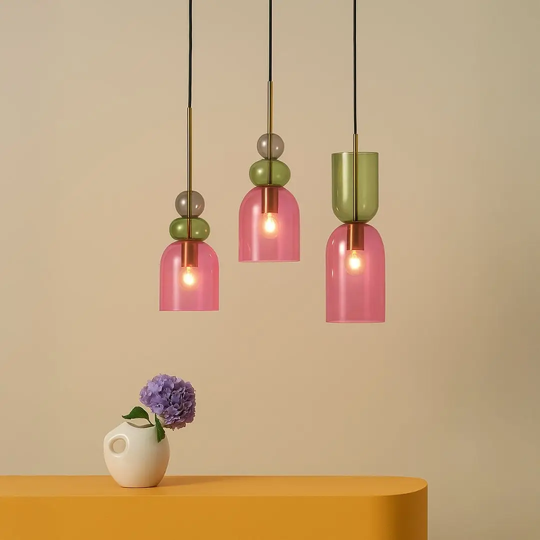 Green and pink glass pendant lights above console table adding vibrant modern lighting to stylish interior decor.