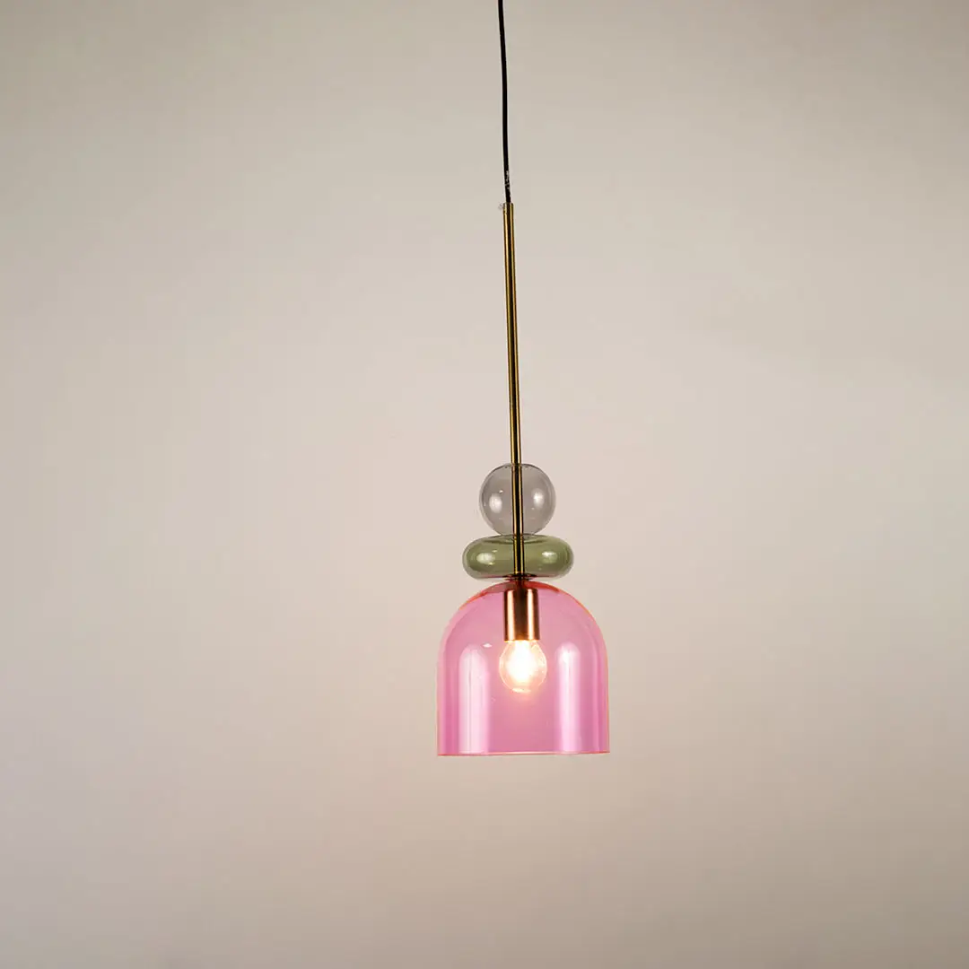 Green and pink glass pendant light illuminated to display stylish hanging light design with soft ambient glow.