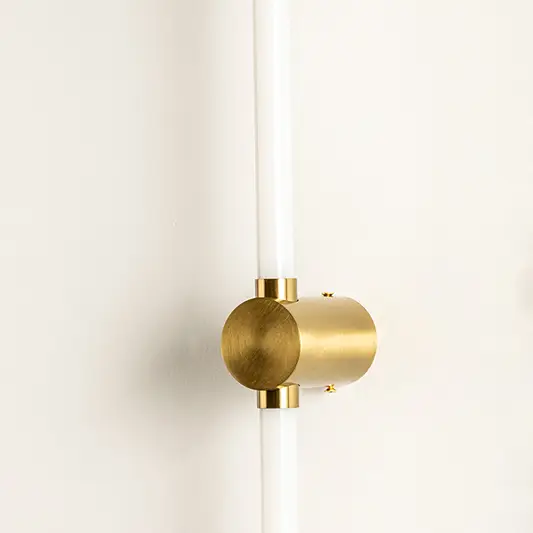 Closeup of wall light with gold metal cylindrical mount and tube design showcasing premium finish for modern interior decor styling.