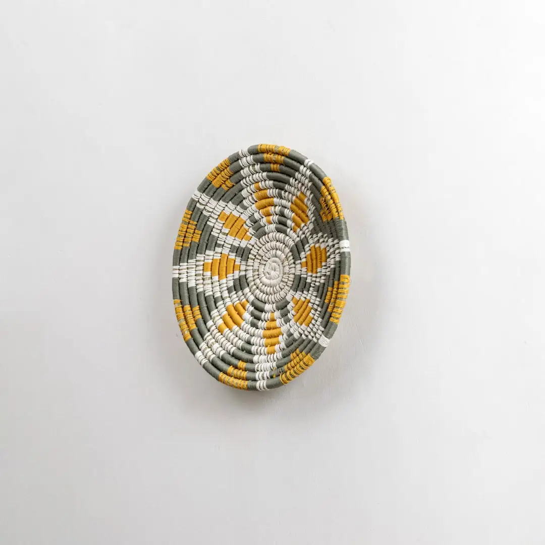 Side angled view of a handcrafted woven wall plate showing its raised textured weaving pattern and natural material detailing.