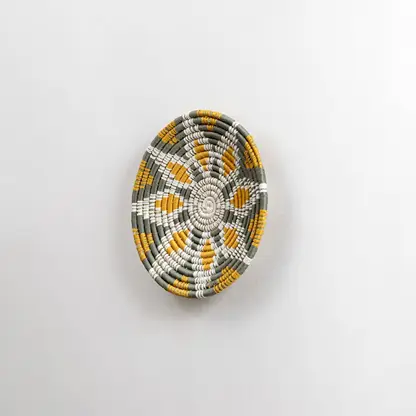 Side angled view of a handcrafted woven wall plate showing its raised textured weaving pattern and natural material detailing.