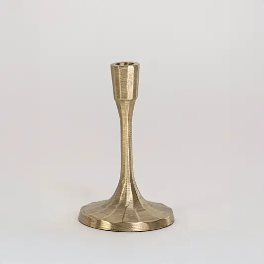 Decorative metal candle holder in gold finish with wide base for table decor or dining styling modern home placement white background.