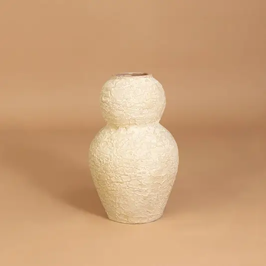 Modern ceramic vase in off white finish with sculpted form for table decor or shelf styling contemporary home placement neutral background.
