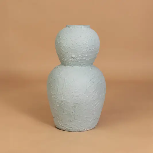 Decorative ceramic vase in light blue finish with textured design for table decor or shelf styling modern home placement neutral background.