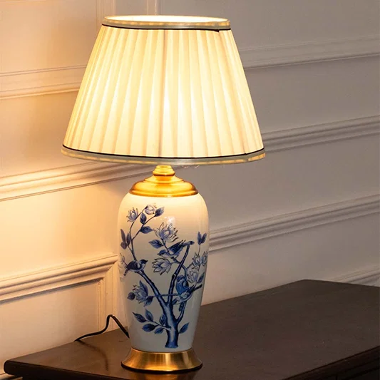 Ceramic table lamp with blue floral detailing and a cream pleated shade providing soft illumination ideal for traditional and modern interiors.