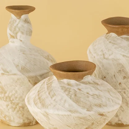 Detailed view of rustic white and brown ceramic vases highlighting natural handmade swirl texture and organic design.