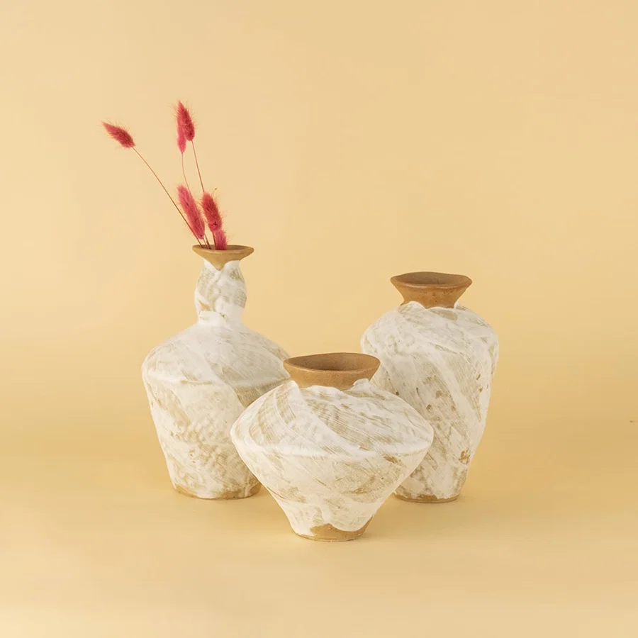 Set of handcrafted white and brown ceramic vases displayed together creating warm organic and artisanal decor styling.
