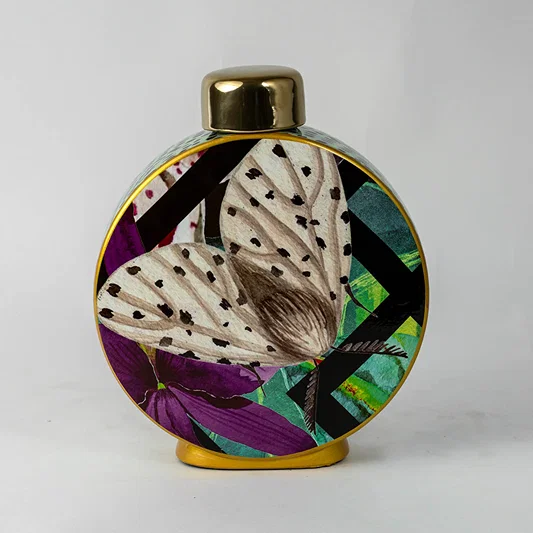 Decorative round ceramic vase with abstract botanical design and gold top placed on white surface against neutral background closeup highlighting vibrant artistic detailing.