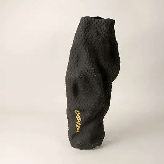 Black sculptural ceramic vase with abstract curved form and matte finish placed on white surface against neutral background showcasing modern artistic decor styling.