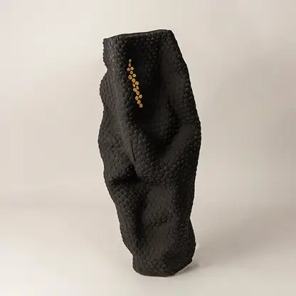 Matte black sculptural ceramic vase with gold accent dots on white background showcasing elegant handcrafted artistry.