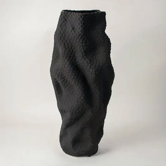 Side view of textured black ceramic vase showing wavy sculptural form and artistic handcrafted detailing on matte surface.