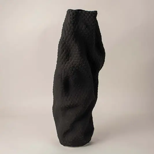 Sculptural black ceramic vase with detailed scale-like texture and organic design on clean white background for display.