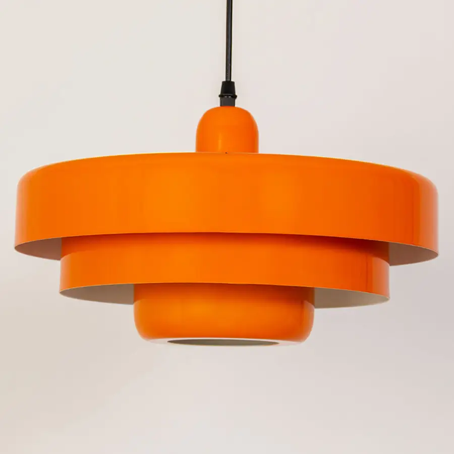 Closeup pendant light in orange metal finish with layered shade design for kitchen or dining decor lighting white background.