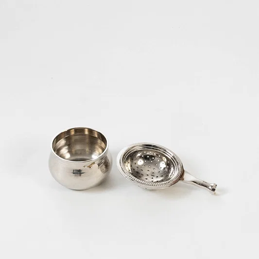 Decorative metal bowl set in silver finish with spoon for dining table or serving decor accessory placement white background.