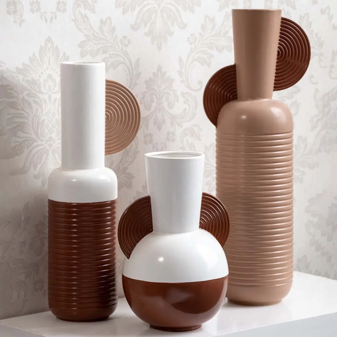Collection of three white and brown geometric ceramic vases with half disc accents and ribbed patterns for decor.
