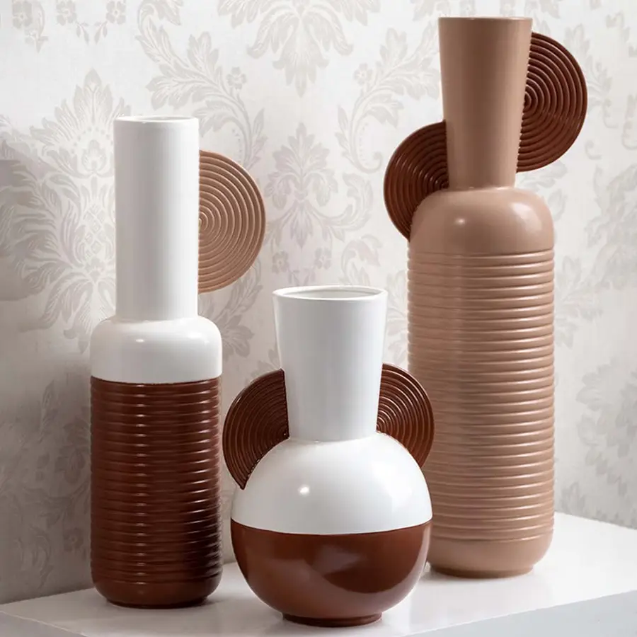 Collection of three white and brown geometric ceramic vases with half disc accents and ribbed patterns for decor.