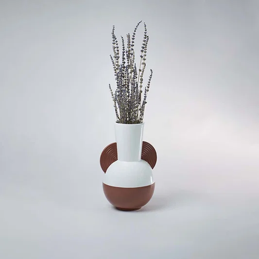 White and brown bulbous ceramic vase with half disc accents styled with dried lavender on a clean white background.