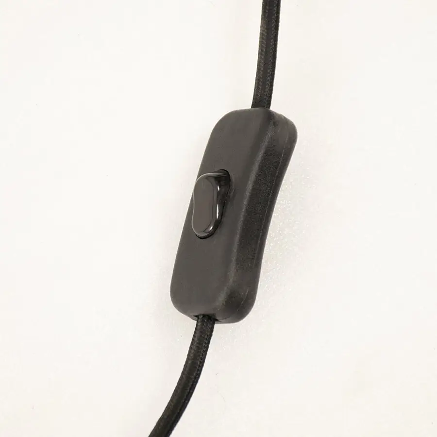 Close up of a black inline power switch attached to the cord of a table lamp shown against a light background.