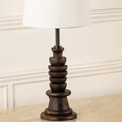 Closeup view of table lamp highlighting its carved dark wooden base and white tapered shade showcasing refined craftsmanship for interior home decor lighting.