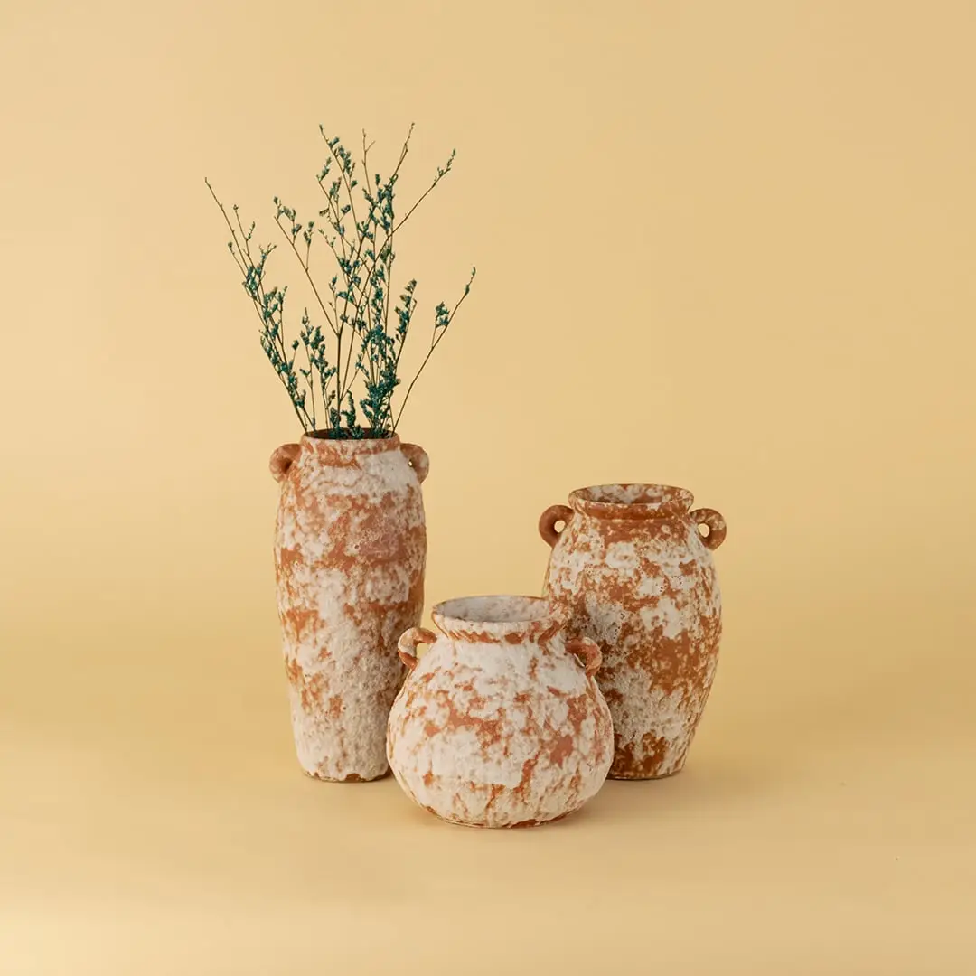 Collection of rustic terracotta ceramic vases in earthy orange white texture styled together for tabletop decoration.