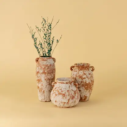 Collection of rustic terracotta ceramic vases in earthy orange white texture styled together for tabletop decoration.