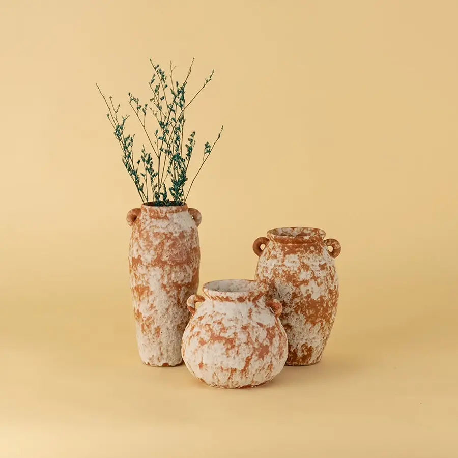 Collection of rustic terracotta ceramic vases in earthy orange white texture styled together for tabletop decoration.