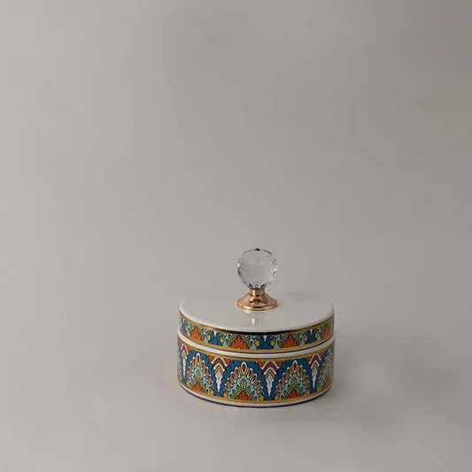 Small ceramic jar with geometric pattern and glass knob lid placed on white surface against neutral background showcasing stylish modern home decor accent.