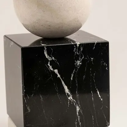 Black marble decorative sculpture with beige stone sphere for luxury shelf styling and contemporary home decor.